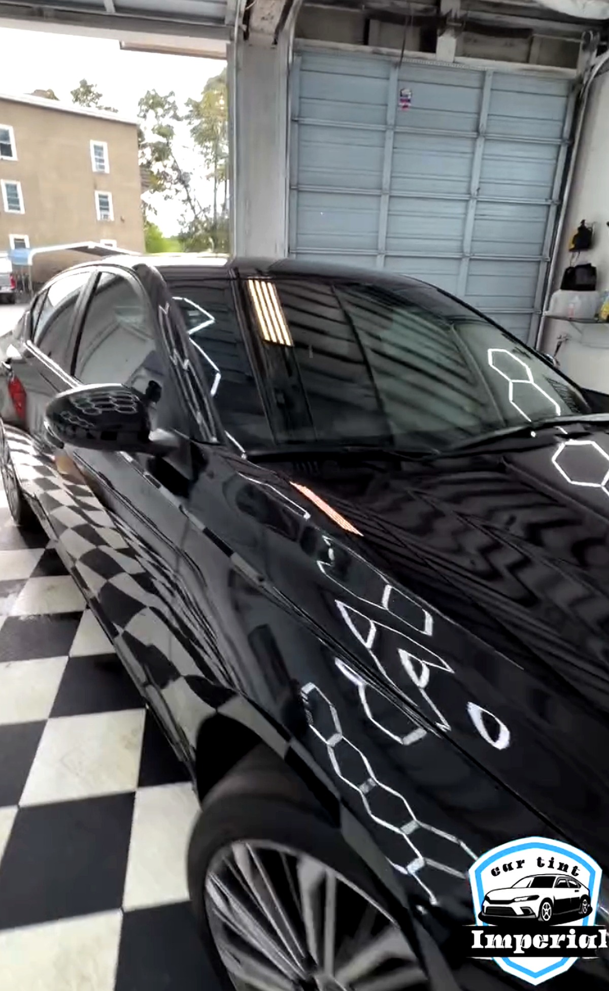 Black sedan with fresh window tint under hexagon lights at Imperial Car Tint